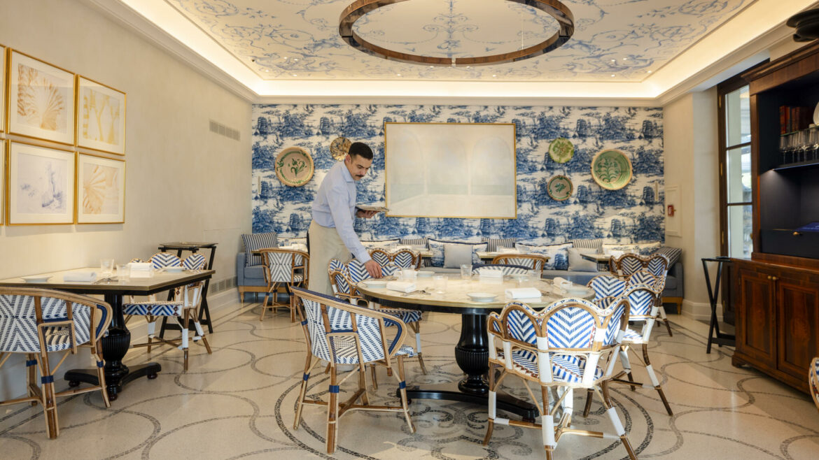Dining room with blue and white details, with a waiter setting up the table
