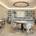 Dining room with blue and white details, with a waiter setting up the table