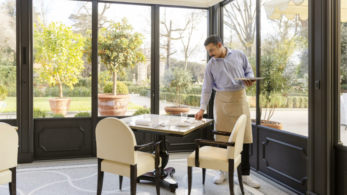Dining room in Onde sunroom with a waiter setting up the table